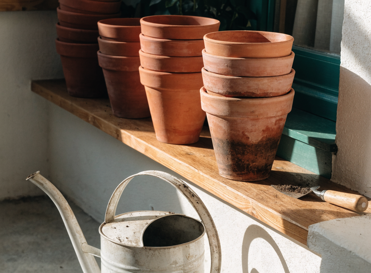 Coin de rempotage avec pots en terre cuite empilés et arrosoir Image